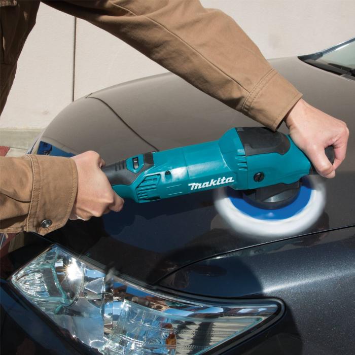 A person using a teal Makita Car Shiner Machine to buff a dark car body in an outdoor setting.
