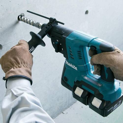 Makita Cordless Rotary Hammer in teal and black colour with white makita being used by a person  