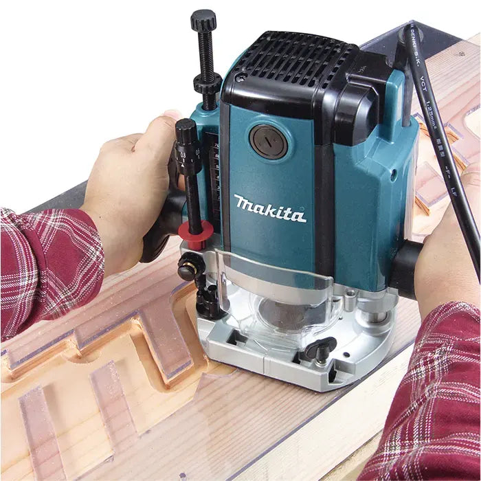 A Makita Wood Router Machine being used by a person to carve a wooden panel, shown in a close-up action shot with the user's hands visible.