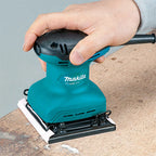 Person using a teal and black Makita Sander on wood