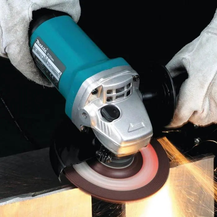 Person using a Makita angle grinder on a dark background