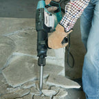 Person using a Makita Electric Concrete Breaker, to break up stone pavement
