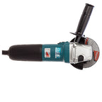 A Makita angle grinder with a black and teal body, a silver metal guard, and a gray abrasive disc, shown from a side profile on a white background.