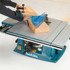 Makita table saw with a person using it to cut wood on a white background