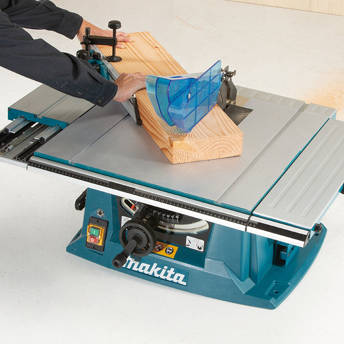 Makita table saw with a person using it to cut wood on a white background