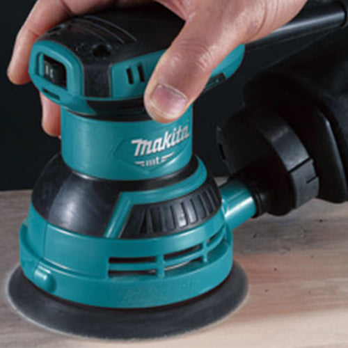 Person holding a Makita Sander Machine For Wood, in teal and black colour with white Makita logo
