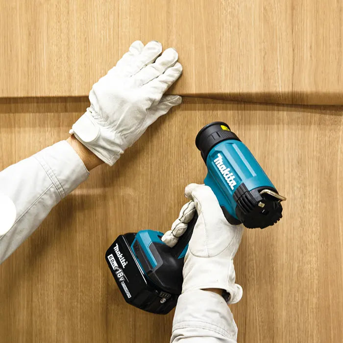 Person using a Makita hot gun on wooden surface