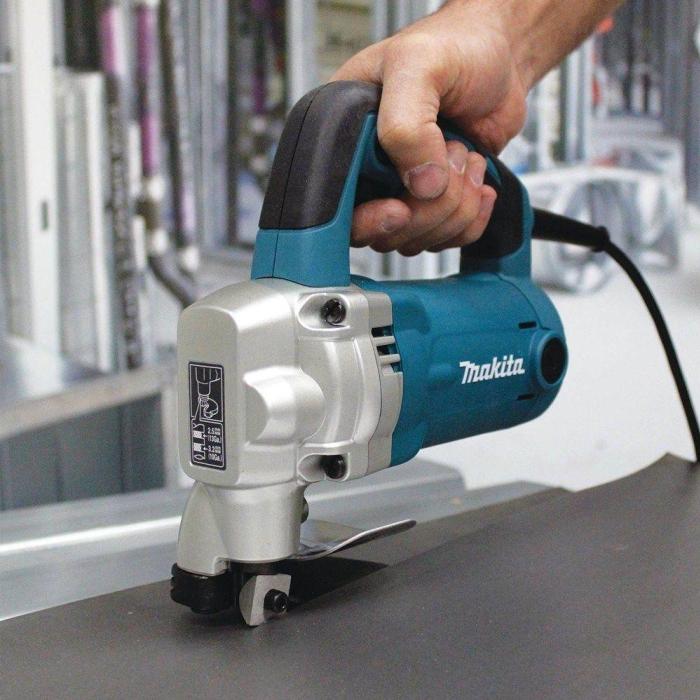 Hand holding a Makita Metal Shearing Machine,on a blurred indoor background