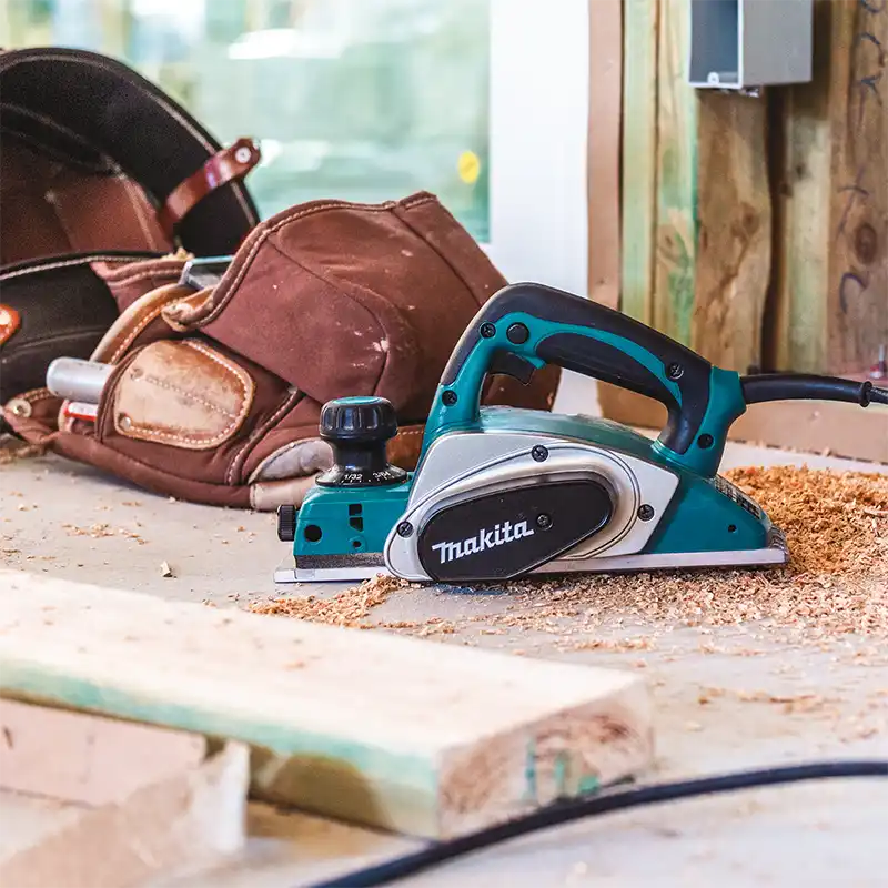 Makita power tool on a workbench with a helmet in the background