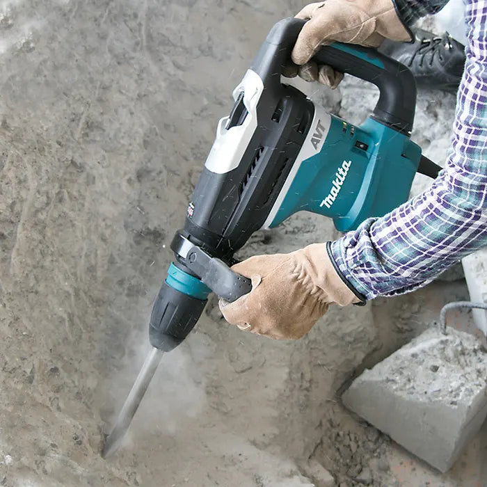 Person using a Makita hammer drill on concrete.